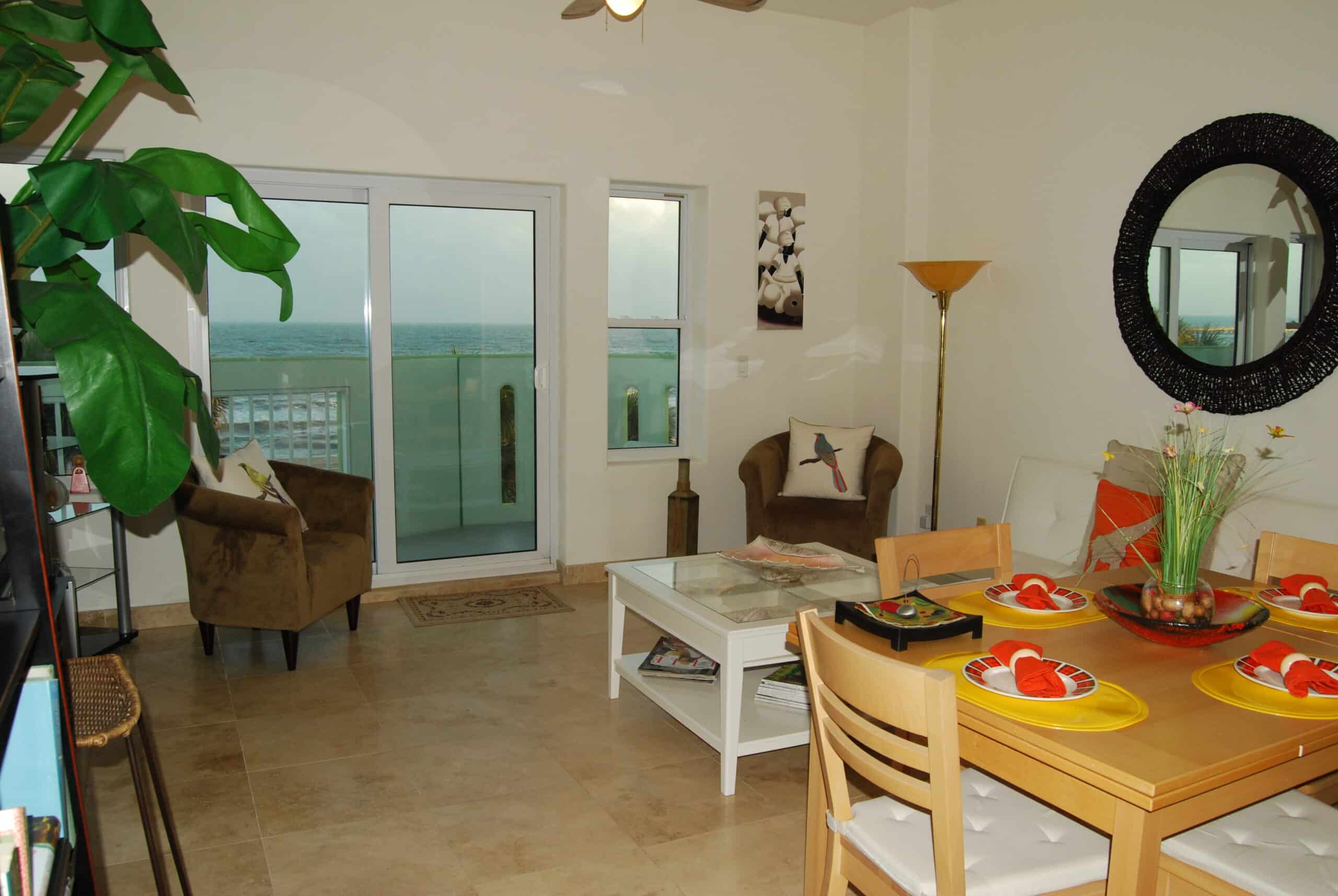 Photo of dining and living area with view of balcony and Gulf through window at Ocean Grove Condominiums