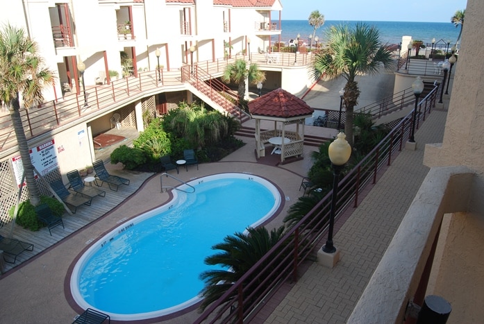 Photo of swimming pool with view of Gulf in the distance at Palms Condominiums