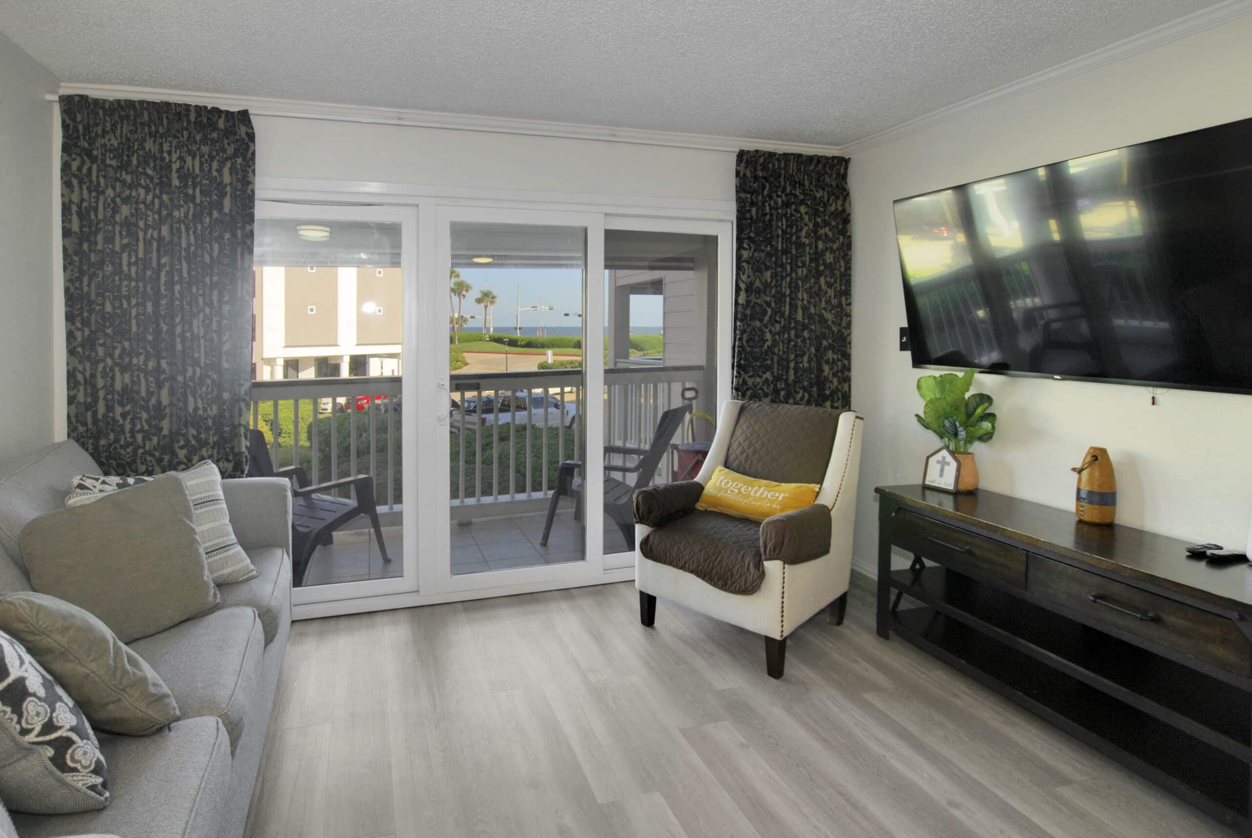 Photo of living room with view of balcony and Gulf through window at Casa Del Mar Condominiums