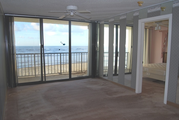 Photo of empty living room with view of beachfront through windows at West Beach Grand Condominiums